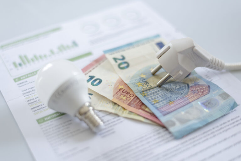 a white electric cap, a light bulb and euro banknotes on an electric bill. Increase in the cost of electricity for residential customers and business users. Payment of electricity bills. Increasing the concept of electricity prices